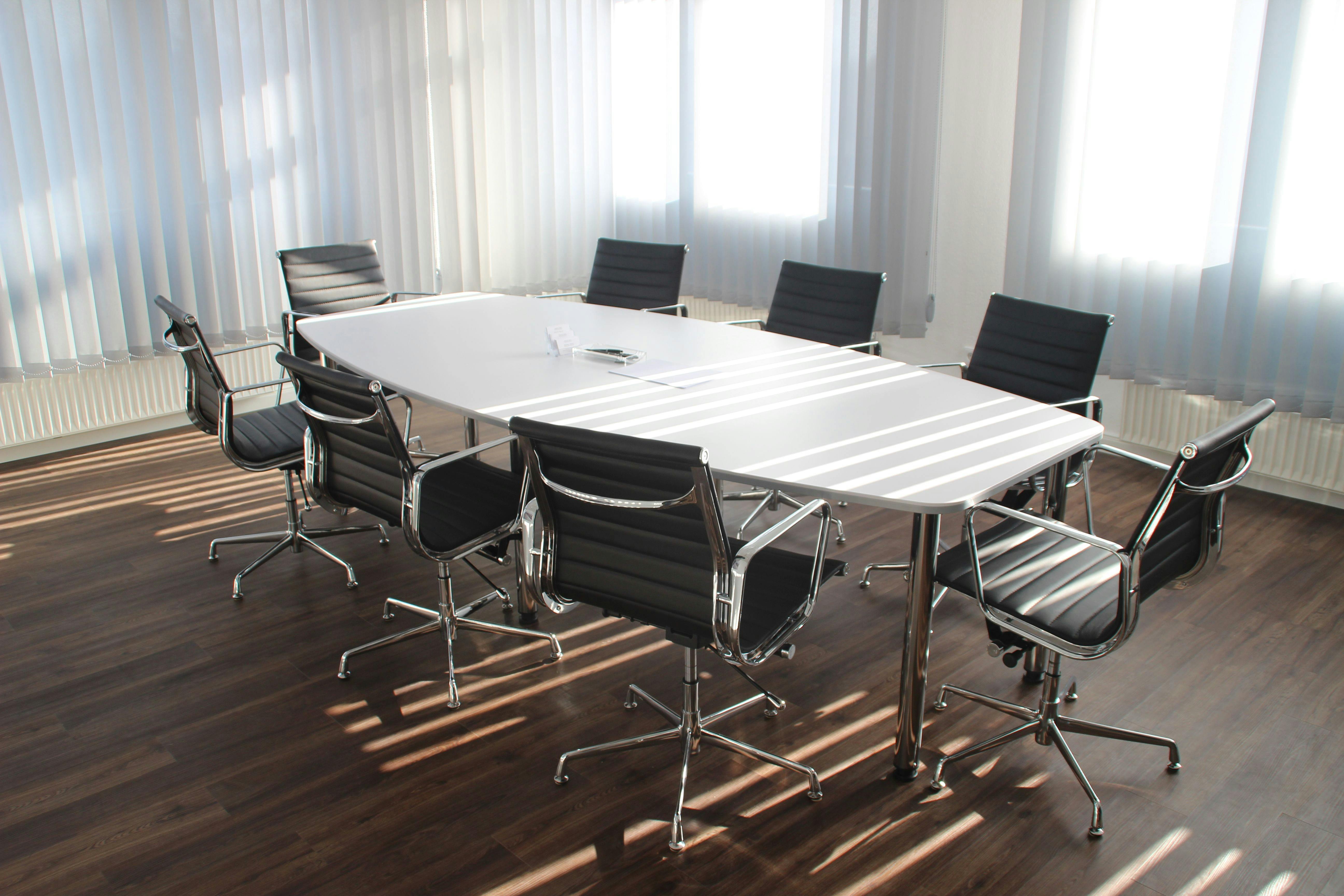 An image of an oval conference table surrounded by 8 executive chairs.