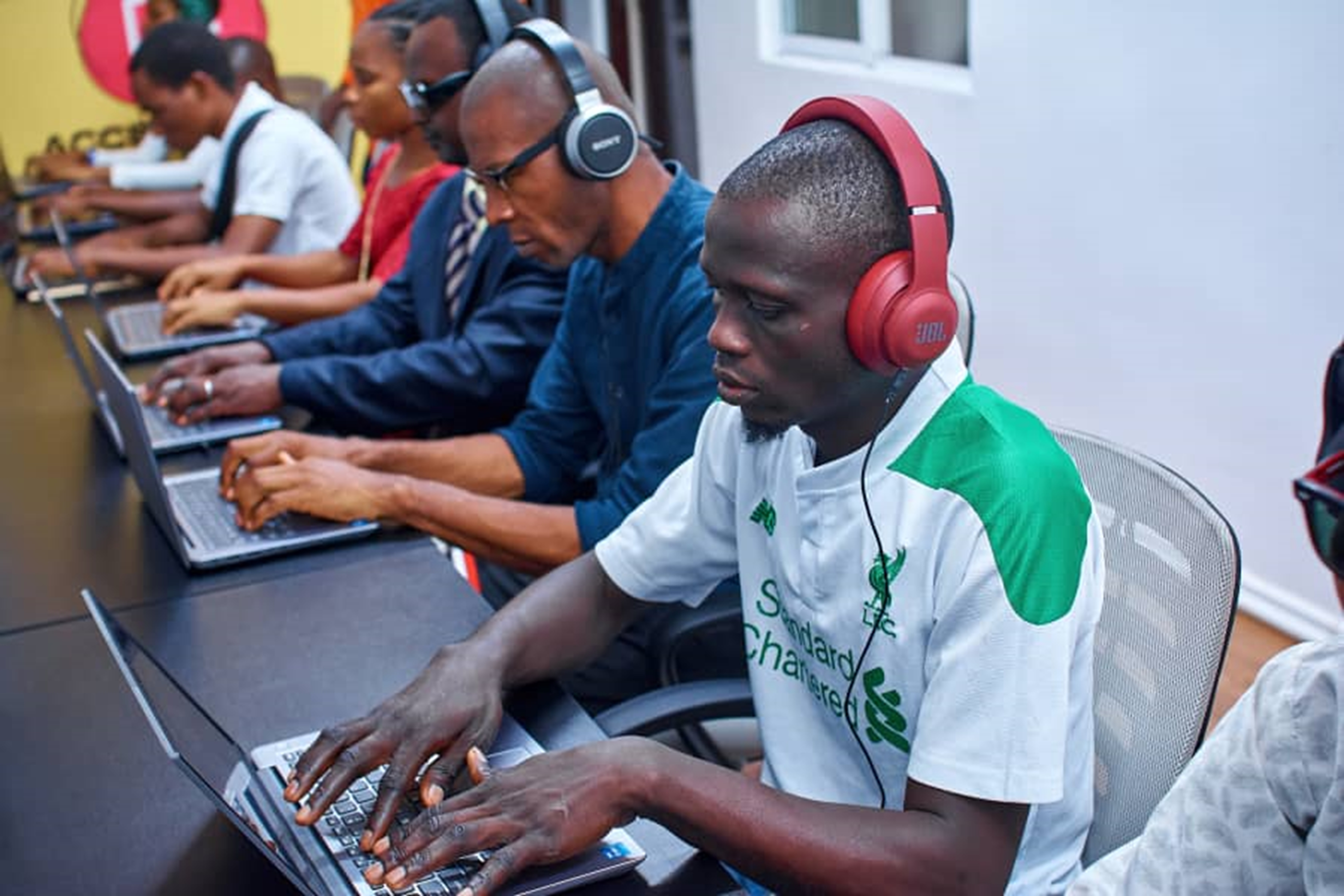 Blind individuals participating in a training session, each with a computer and headset in front of them